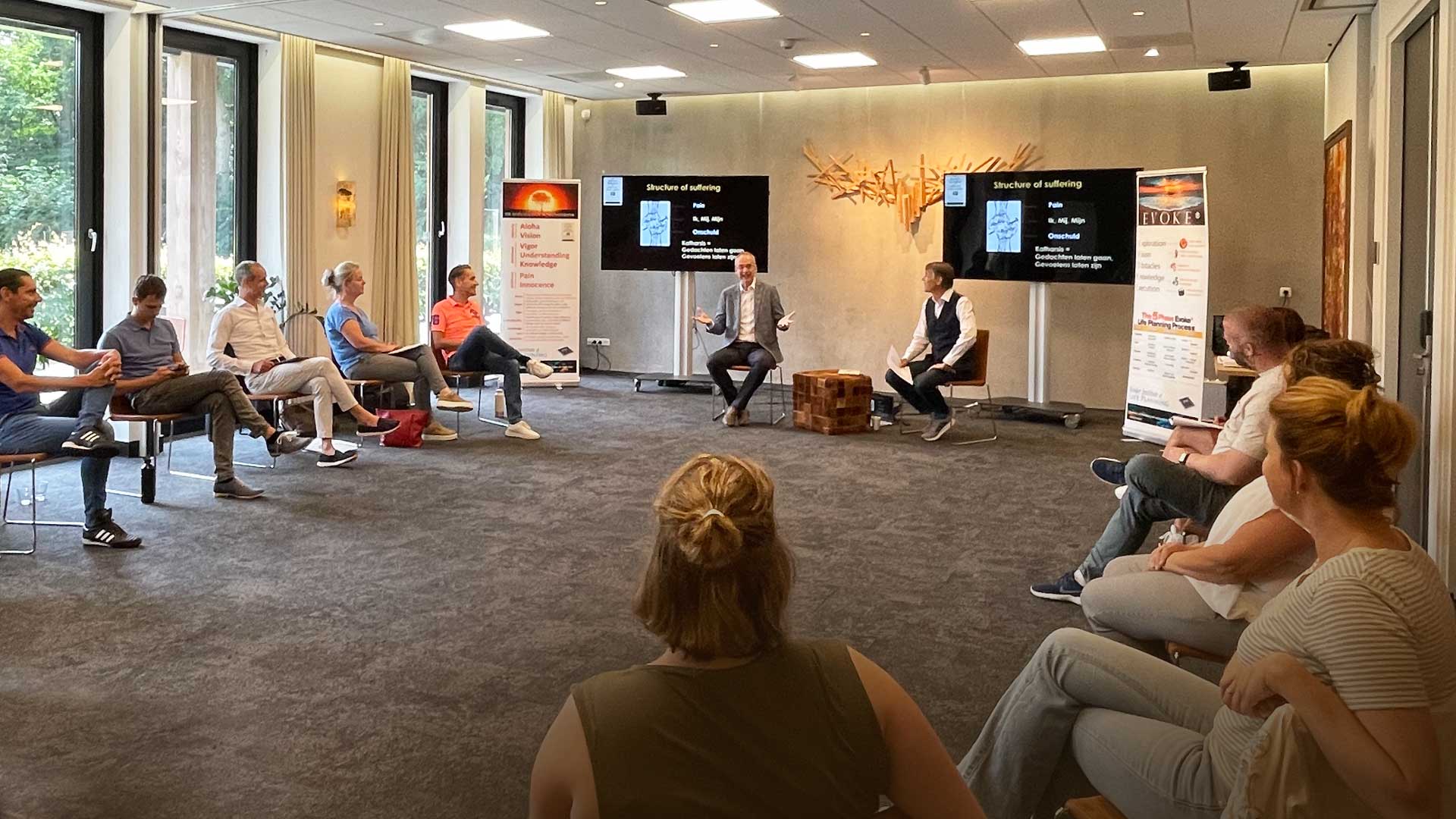 Three adults sitting in chairs, facing each other